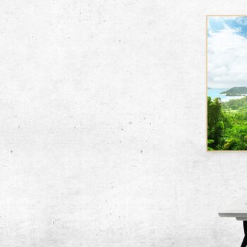 Buntes Bild von einer Inselaussicht hängt über einem Schreibtisch an einer grauen Betonwand
